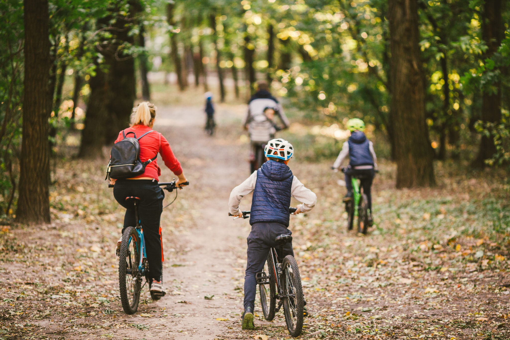 parents and kids cycling on forest trail. Young family cycling in autumn park. Family mountain biking on forest. Theme family active sports outdoor recreation. Family Cycling Through Fall Woodland.